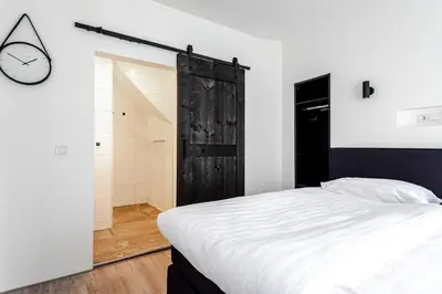 a bedroom with a bed and a clock on the wall at Kings Square in Zandvoort