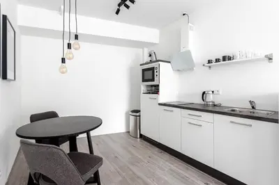 a kitchen with white cabinets and a table and chairs at Kings Square in Zandvoort