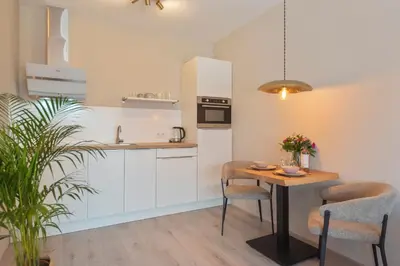a kitchen with white cabinets and a table with chairs at Kings Square in Zandvoort