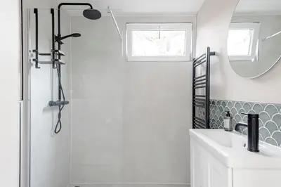 a white bathroom with a shower and a sink at The Garden Suite in Zandvoort