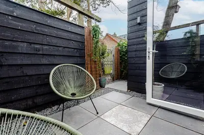 a patio with two chairs and an open door at The Garden Suite in Zandvoort