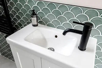 a white sink in a bathroom with a green wall at The Garden Suite in Zandvoort