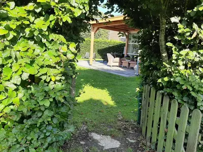 a garden with a wooden fence and a chair in a yard at Gastehuisie Lekkerslaap in Zeewolde