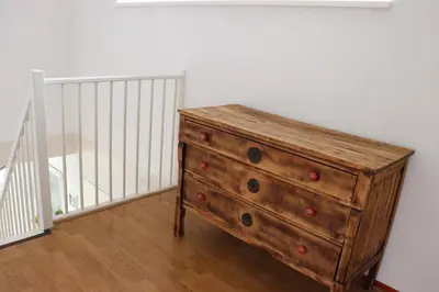 a wooden dresser in a room with a staircase at Gastehuisie Lekkerslaap in Zeewolde