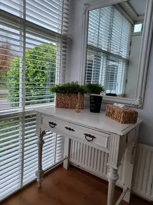 a white table with plants on it next to a window at Gastehuisie Lekkerslaap in Zeewolde