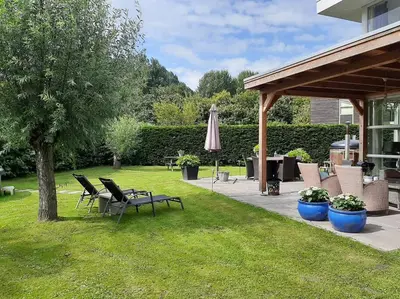 a patio with a table and chairs and an umbrella at Gastehuisie Lekkerslaap in Zeewolde