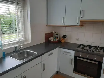 a kitchen with white cabinets and a sink at Gastehuisie Goedemoed in Zeewolde