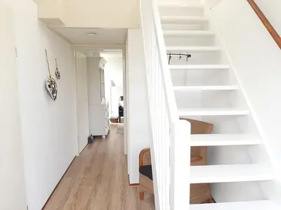 a white staircase in a home with white walls and wood floors at Gastehuisie Goedemoed in Zeewolde