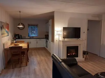 a kitchen and living room with a fireplace and a table at Gastehuisie Goedemoed in Zeewolde