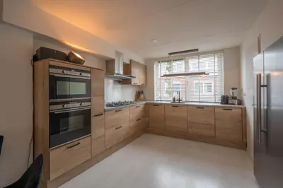 a kitchen with wooden cabinets and stainless steel appliances at Meerzicht 99 - Luxury house 30 minutes from Amsterdam in Uitgeest