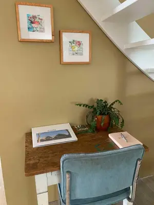 a table with a blue chair and pictures on the wall at Smederij Abbekerk, guesthouse in Abbekerk