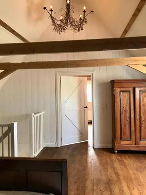 an attic room with a door and a chandelier at Smederij Abbekerk, guesthouse in Abbekerk