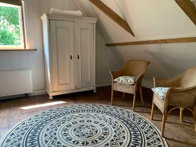 a room with two chairs and a cabinet and a rug at Smederij Abbekerk, guesthouse in Abbekerk