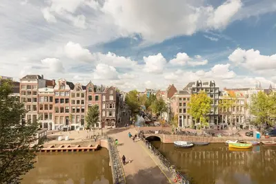 a bridge over a river in a city with buildings at The Red Ox - Super Central Canal View Rooms in Amsterdam