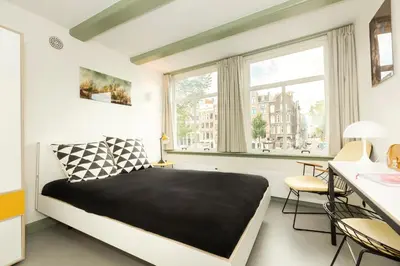 a bedroom with a bed and a table and chairs at The Red Ox - Super Central Canal View Rooms in Amsterdam