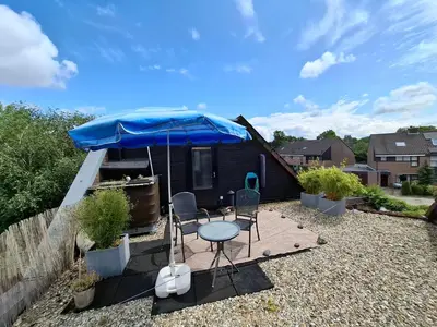 a patio with a table and chairs and a blue umbrella at StudioRandijk in Nieuwegein