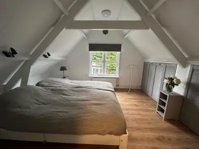a bedroom with a large bed and a window at De Lijster in Bergen