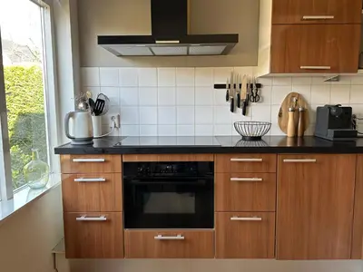 a kitchen with wooden cabinets and a black oven at De Lijster in Bergen
