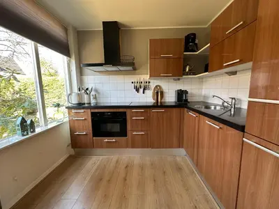 a kitchen with wooden cabinets and a large window at De Lijster in Bergen