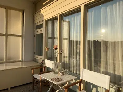 a balcony with a table and chairs and a window at Amstel BeachHouse Egmond aan Zee, 50m from the beach! in Egmond aan Zee