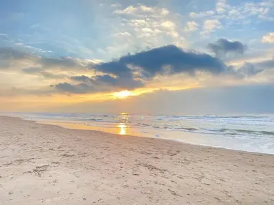 a sunset on a beach with the ocean at Amstel BeachHouse Egmond aan Zee, 50m from the beach! in Egmond aan Zee