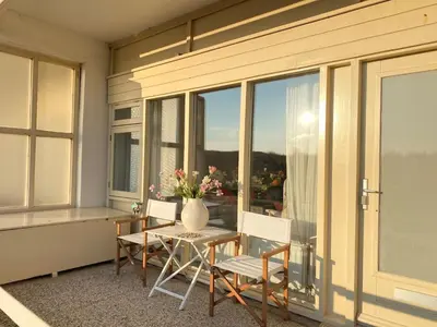 a room with a table and chairs and a vase with flowers at Amstel BeachHouse Egmond aan Zee, 50m from the beach! in Egmond aan Zee