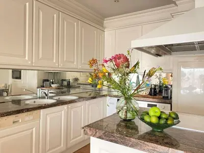 a white kitchen with a vase of flowers on a counter at Amstel BeachHouse Egmond aan Zee, 50m from the beach! in Egmond aan Zee