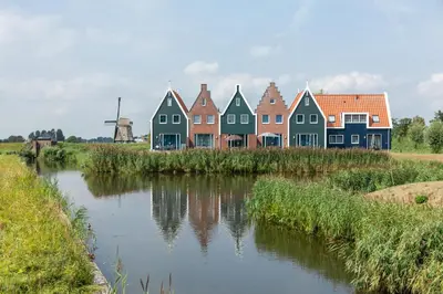 a row of colorful houses next to a river at Marinapark Volendam in Volendam