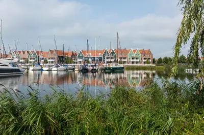 a group of boats docked in a harbor with houses at Marinapark Volendam in Volendam