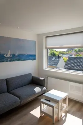 a living room with a couch and a window at Appartement aan Zee in Noordwijk aan Zee
