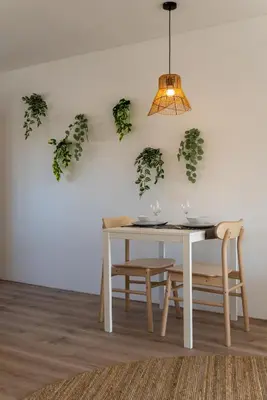a dining room with a white table and plants on the wall at Appartement aan Zee in Noordwijk aan Zee
