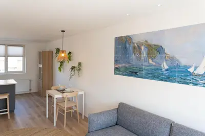 a living room with a couch and a painting on the wall at Appartement aan Zee in Noordwijk aan Zee
