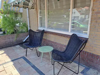 two chairs and a table in front of a building at Appartement aan Zee in Noordwijk aan Zee