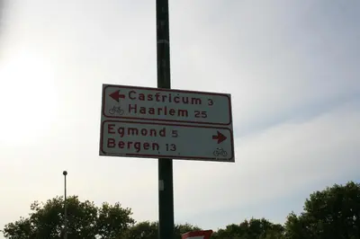 a street sign with arrows on a pole at De Duinlopers - Studio appt Bries - Strand, duinen en nabij cultuur steden in Castricum