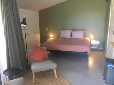 a bedroom with a large bed and a chair at De Duinlopers - Studio appt Bries - Strand, duinen en nabij cultuur steden in Castricum