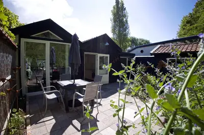 a patio with a table and chairs in a garden at Zandrijk in Egmond aan den Hoef